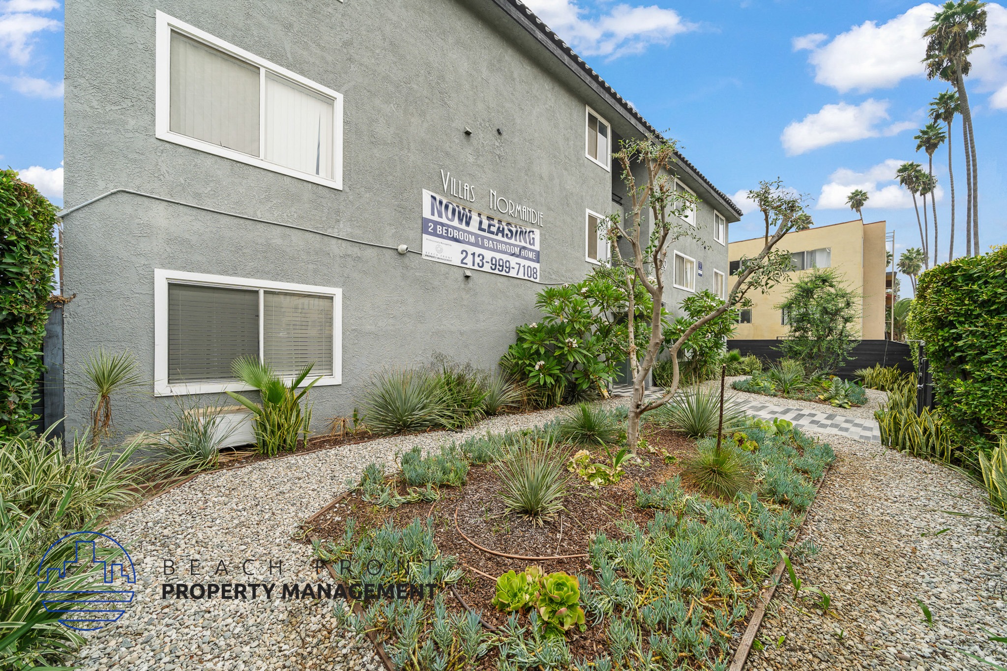 A grey building with a sign that says "Village Homeowners Association" and a phone number.